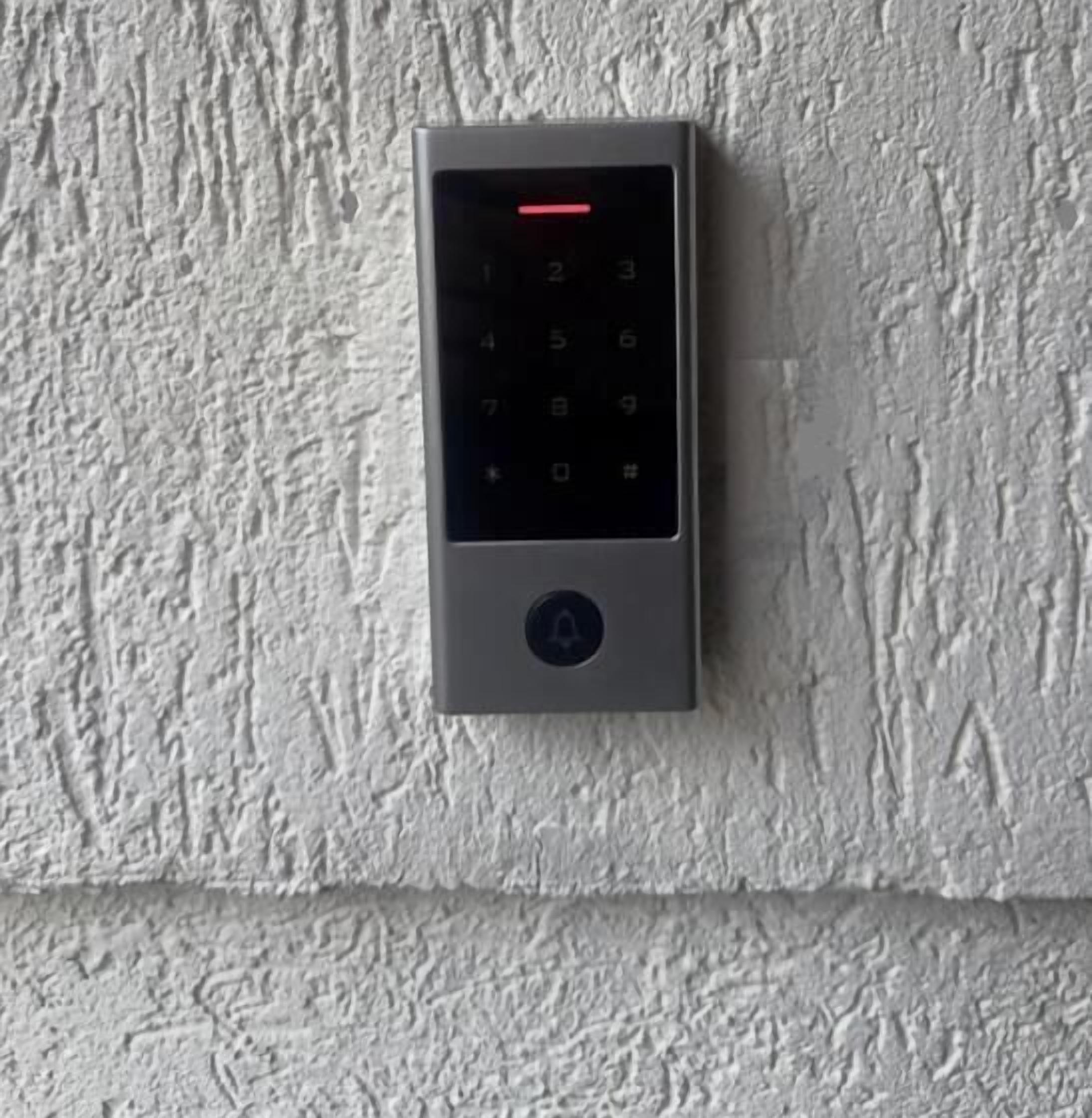 Teclado fixado numa parede texturizada, provavelmente para um sistema de acesso a estacionamento.