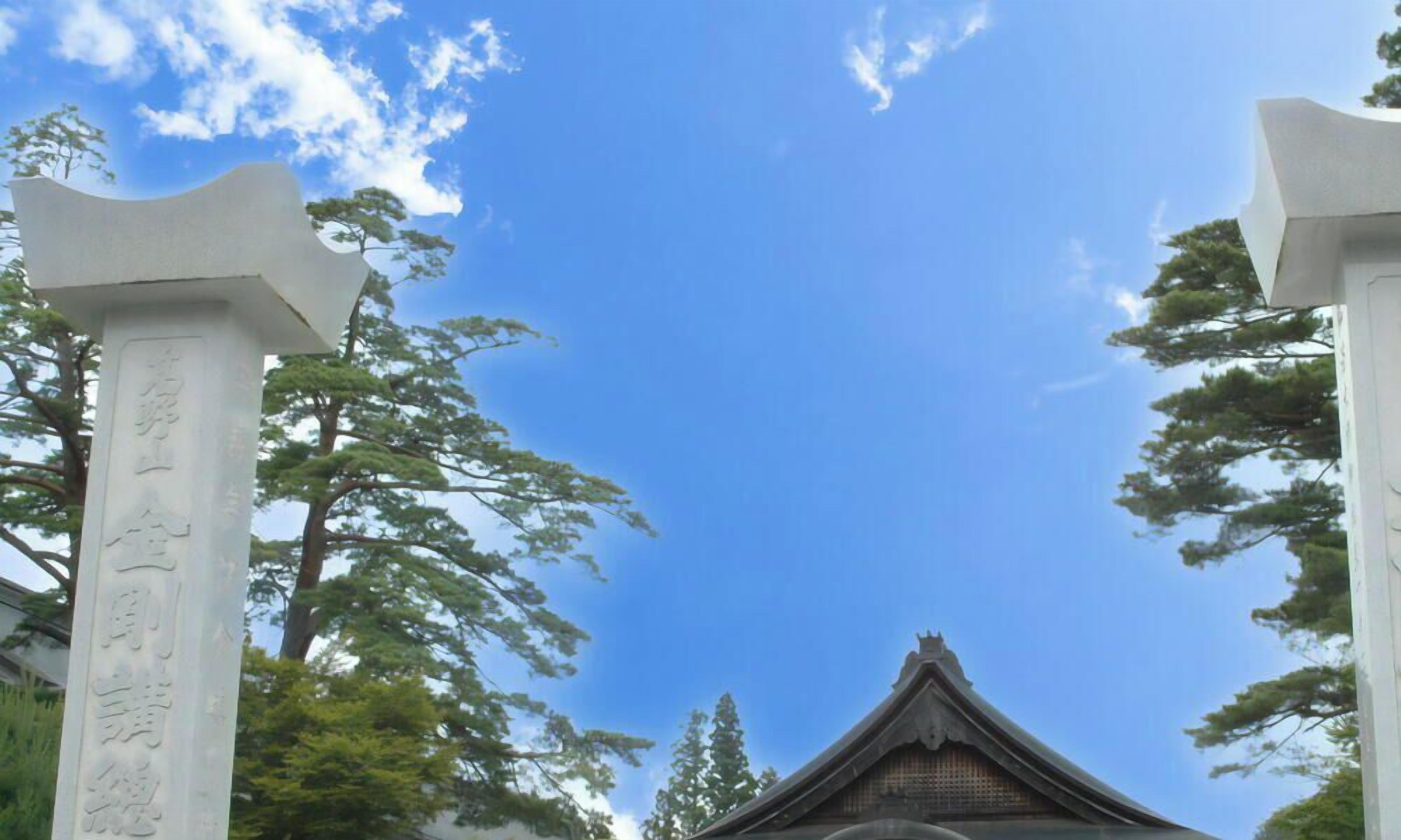 A traditional Japanese building with a large entrance gate and two stone pillars with inscriptions.