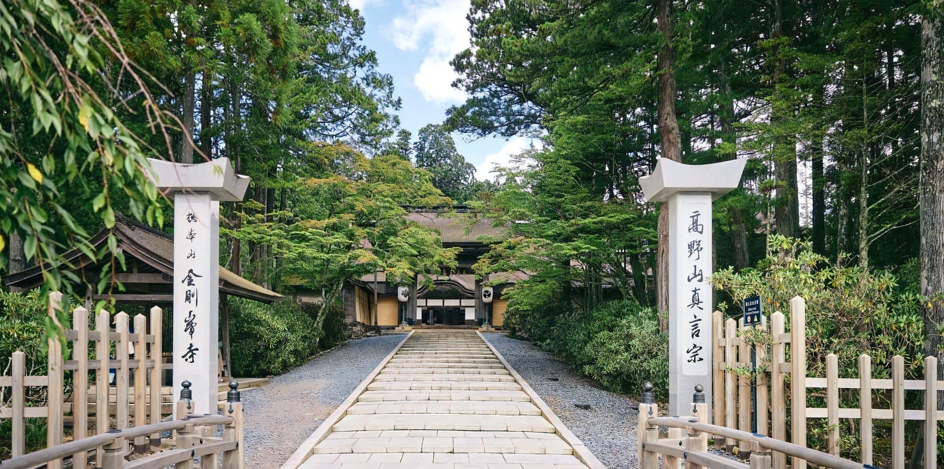 A traditional Japanese temple gate with wooden railings and a stone pathway leading to the temple.