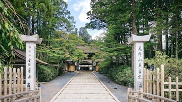Une porte traditionnelle d’un temple japonais, avec des rampes en bois et un chemin de pierre menant au temple.