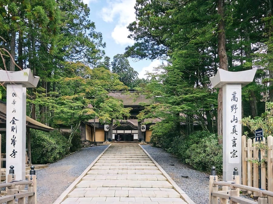 A traditional Japanese temple gate with wooden railings and a stone pathway leading to the temple.