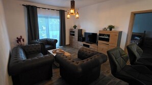 A modern living room with a sofa set, a coffee table, a TV, and wooden cabinets.