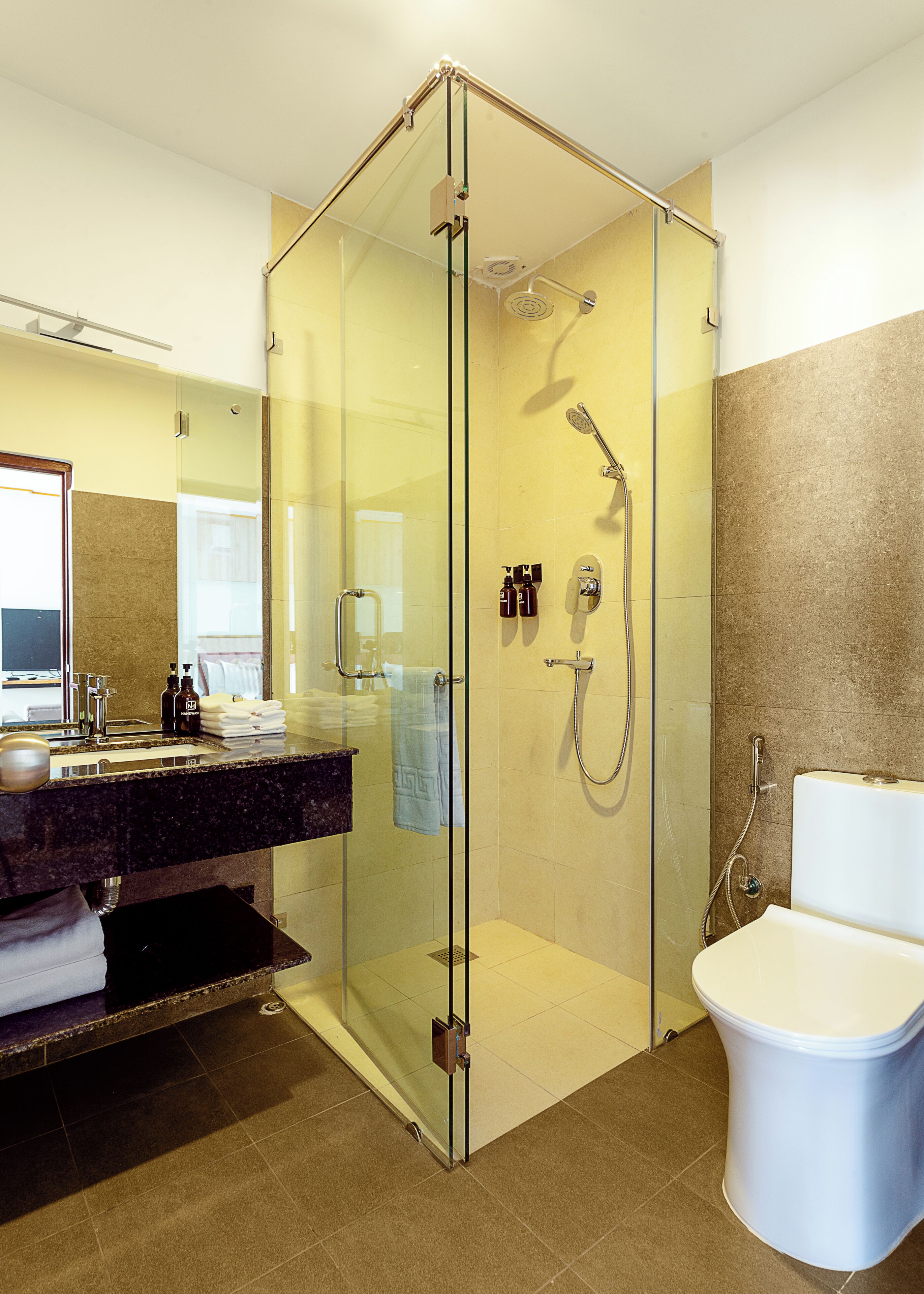 Ein modernes Badezimmer mit einer Duschkabine aus Glas, einem Waschbecken mit Marmorplatte und einer Toilette.