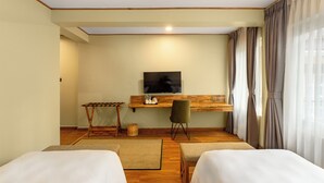 Une chambre d’hôtel avec deux lits, un bureau avec une télévision et une grande fenêtre avec des rideaux.