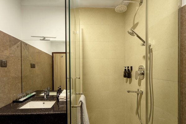 A bathroom with a glass-enclosed shower, a sink, and a mirror. - Nova Tara Hotel Kathmandu (Kathmandu)