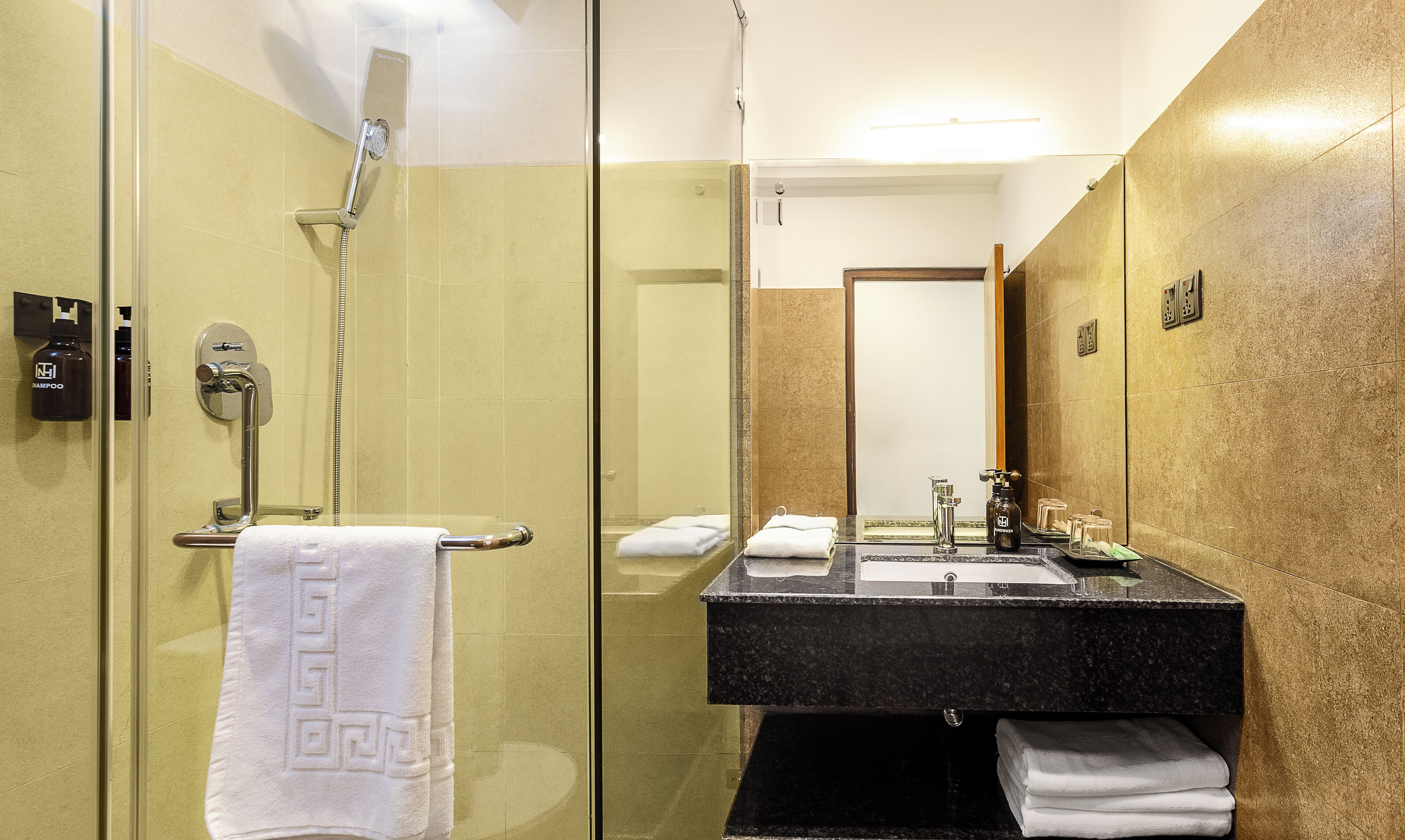 A modern bathroom with a glass-enclosed shower, a black marble sink, and a large mirror.