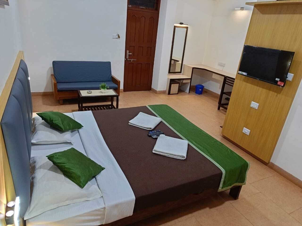 A hotel room with a bed, a desk, a chair, a TV, and a wardrobe.