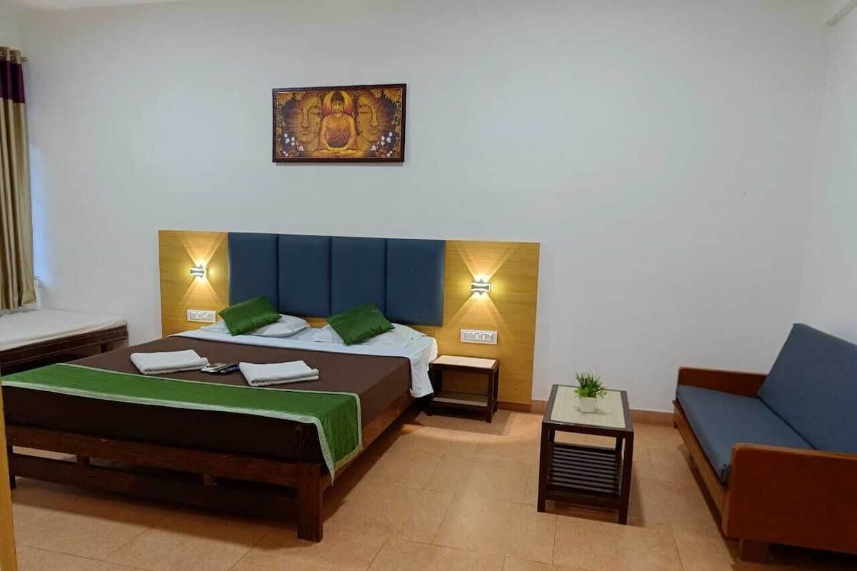 Een slaapkamer met een bed, nachtkastjes, een sofa en een klein tafeltje met een plant.