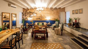 A spacious lobby with a high ceiling, a large mural, comfortable seating, and a staircase leading to an upper level. - Elivaas Bludoor 5-BHK Pet Friendly Villa (Calangute)