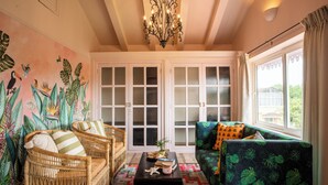 A living room with wicker furniture, a patterned rug, and a tropical mural. - Elivaas Bludoor 5-BHK Pet Friendly Villa (Calangute)