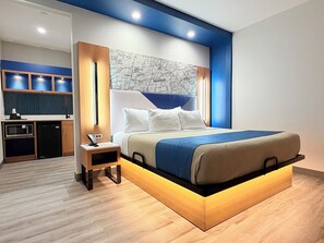Una habitación de hotel moderna con una cama grande, una kitchenette pequeña y un mapa en la pared.