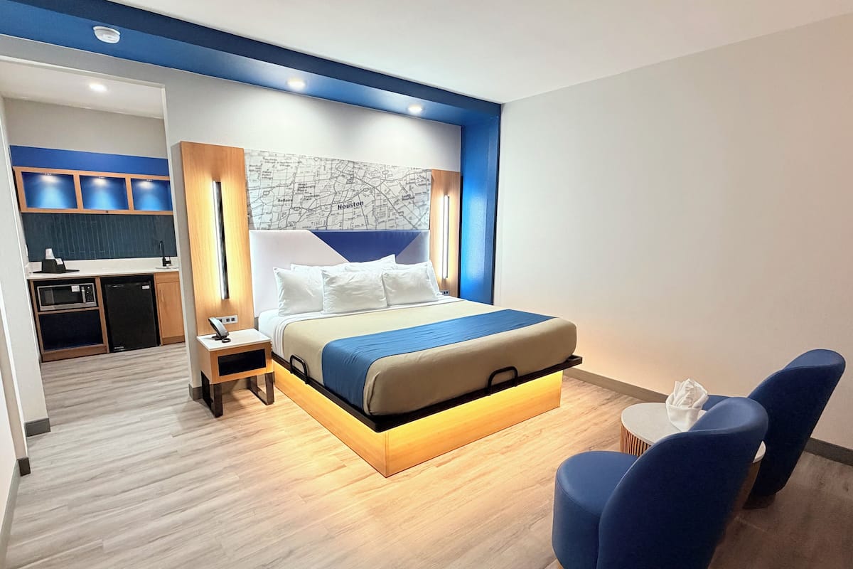 Une chambre d’hôtel moderne équipée d’un grand lit, d’un bureau et d’une kitchenette.