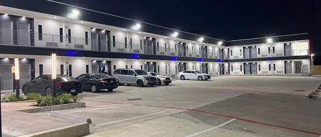 A multi-story motel with several parked cars in front.