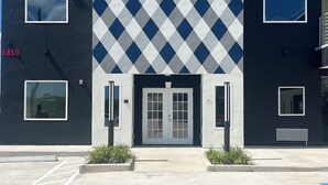 A modern building with a geometric patterned facade, a prominent logo, and a set of double doors. - Crystal Inn - NorthWest - 290 (Houston)
