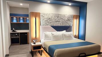 Una habitación de hotel moderna con una cama grande, un mapa en la pared y una kitchenette al fondo.