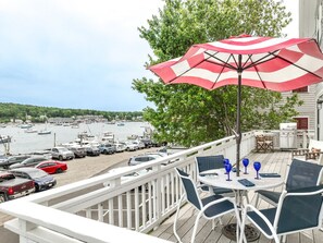 A balcony with a view of a marina, outdoor seating, and a grill area.