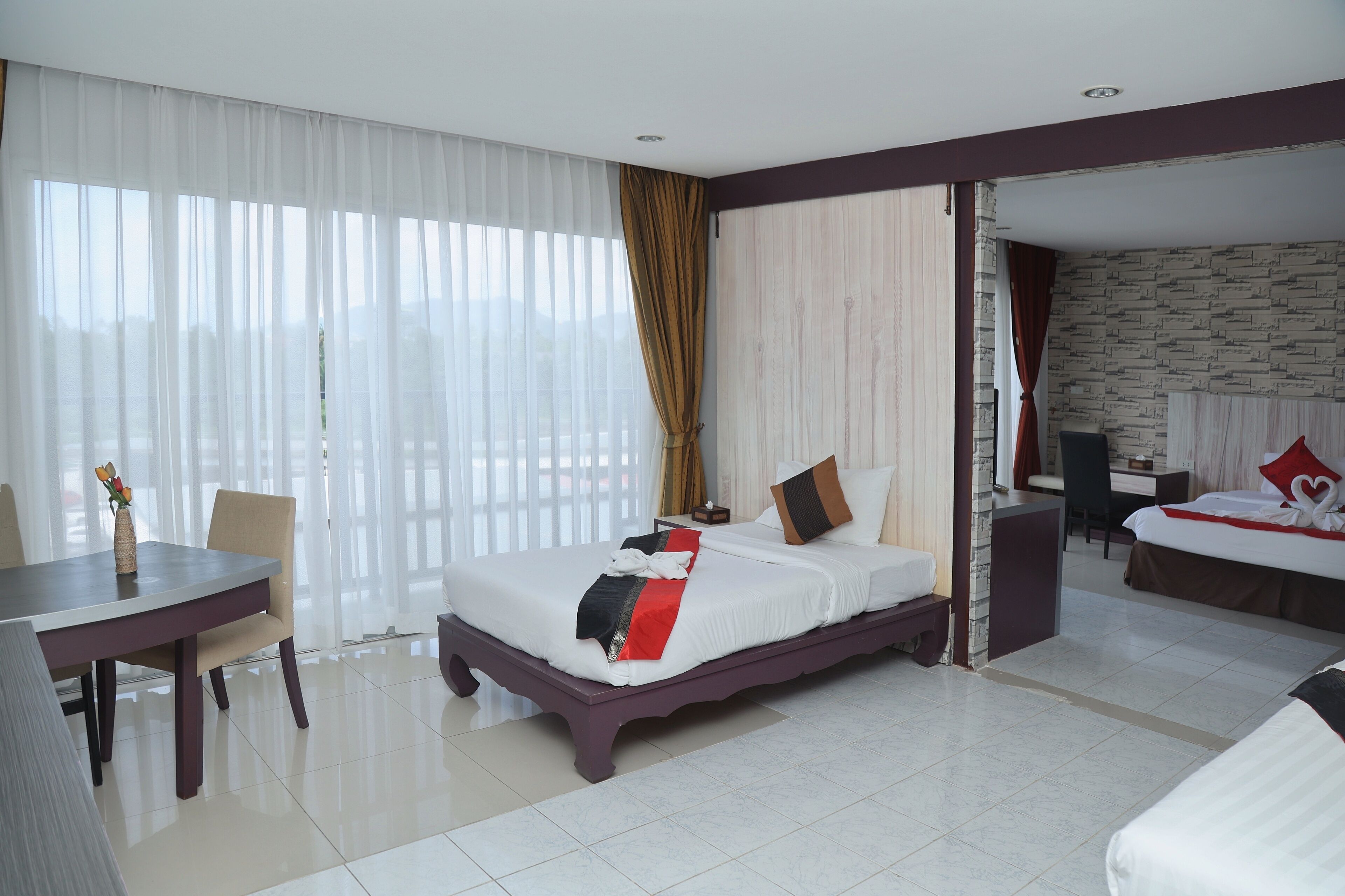 A hotel room with a large bed, a desk, and a dining area.