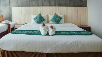 Una cama bien tendida con sábanas blancas, dos almohadas estampadas en verde y un corredor decorativo verde.