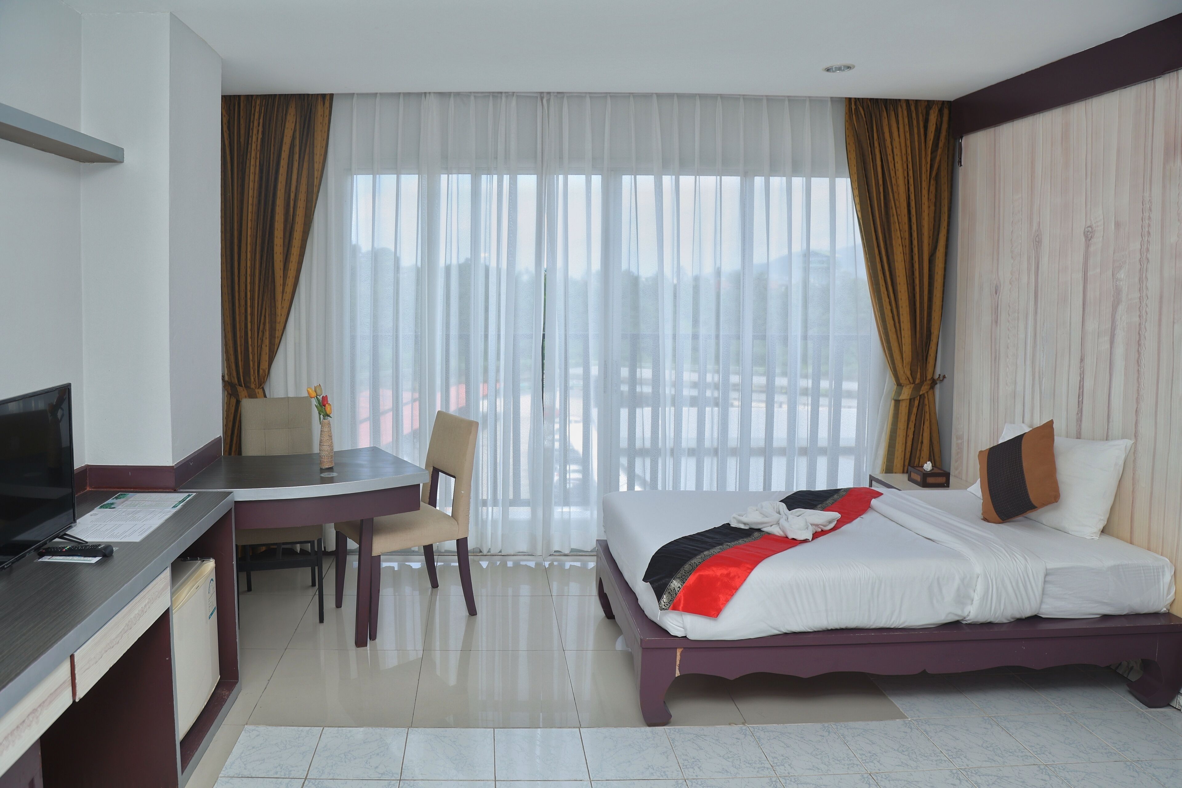 A hotel room with a bed, a desk with a computer, a chair, and a TV.