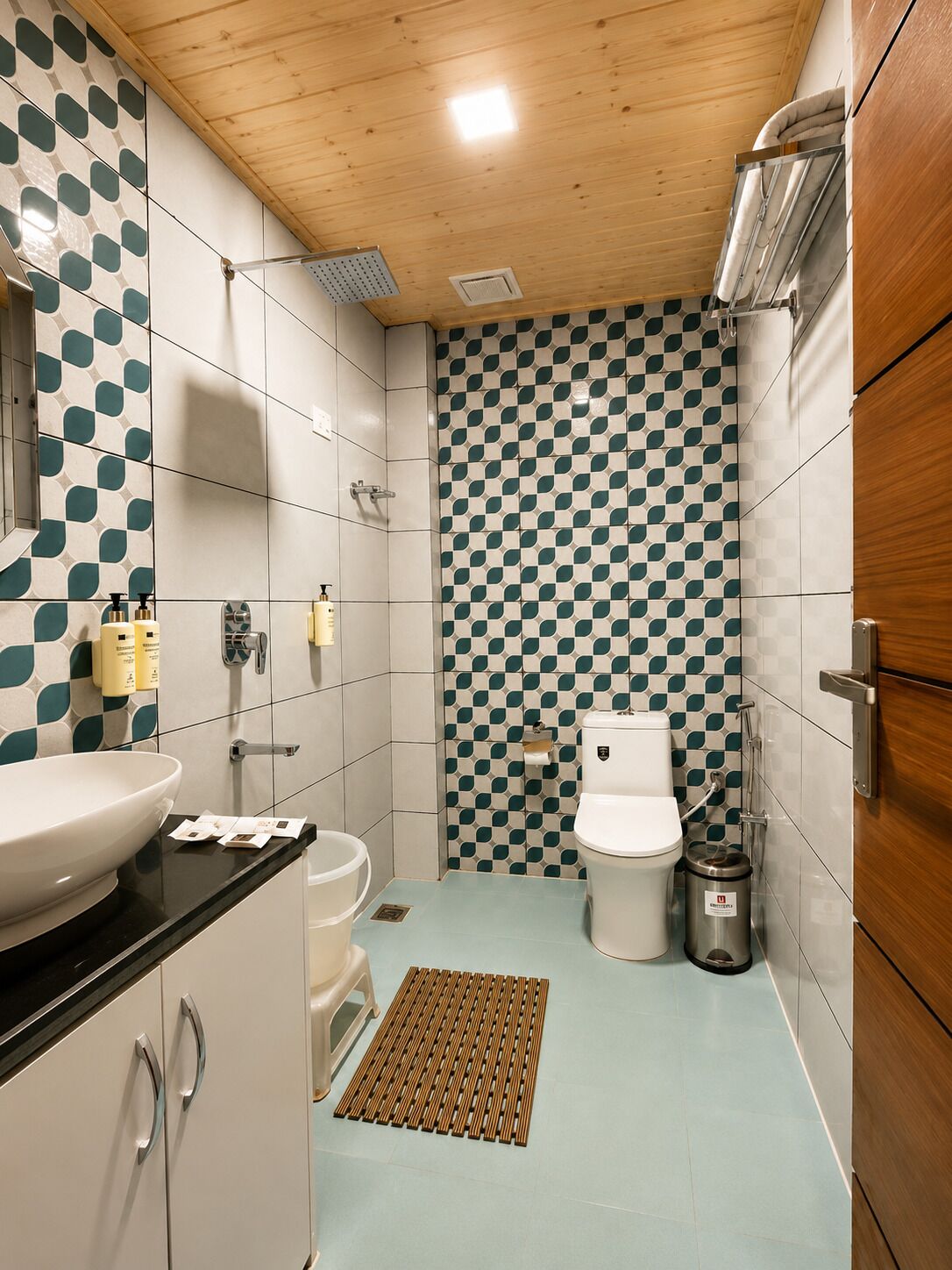 A modern bathroom with a checkered tile wall, a sink, toilet, and a shower.