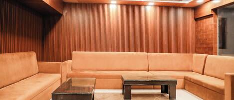 A modern living room with a sectional sofa, two coffee tables, and wooden panel walls.