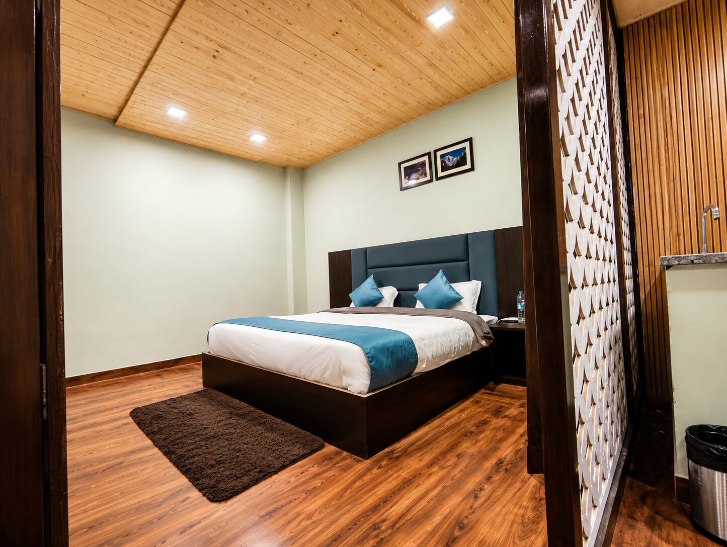 A bedroom with a bed, wooden flooring, a headboard, and a nightstand.