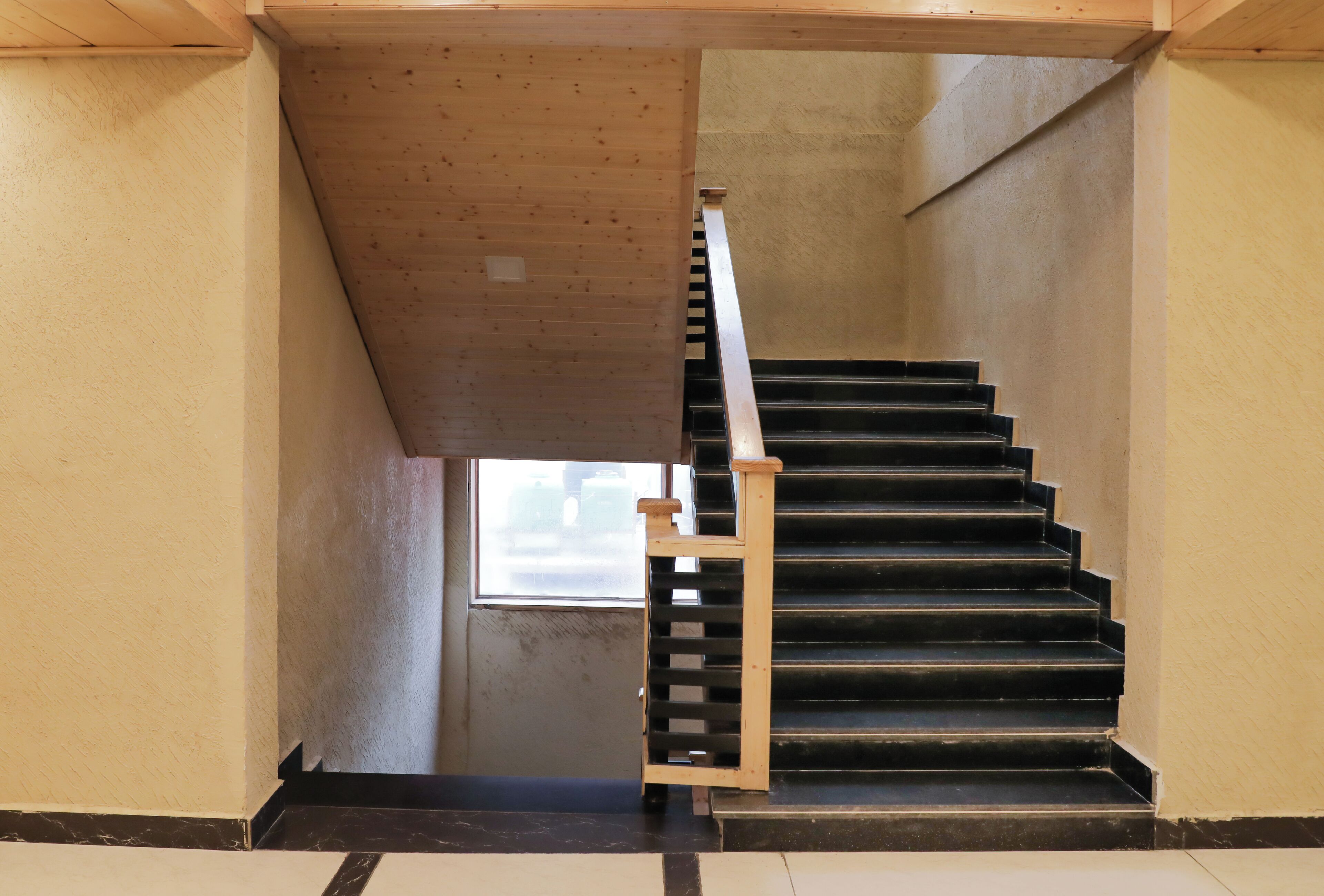 A wooden staircase with a metal handrail leading to a landing.