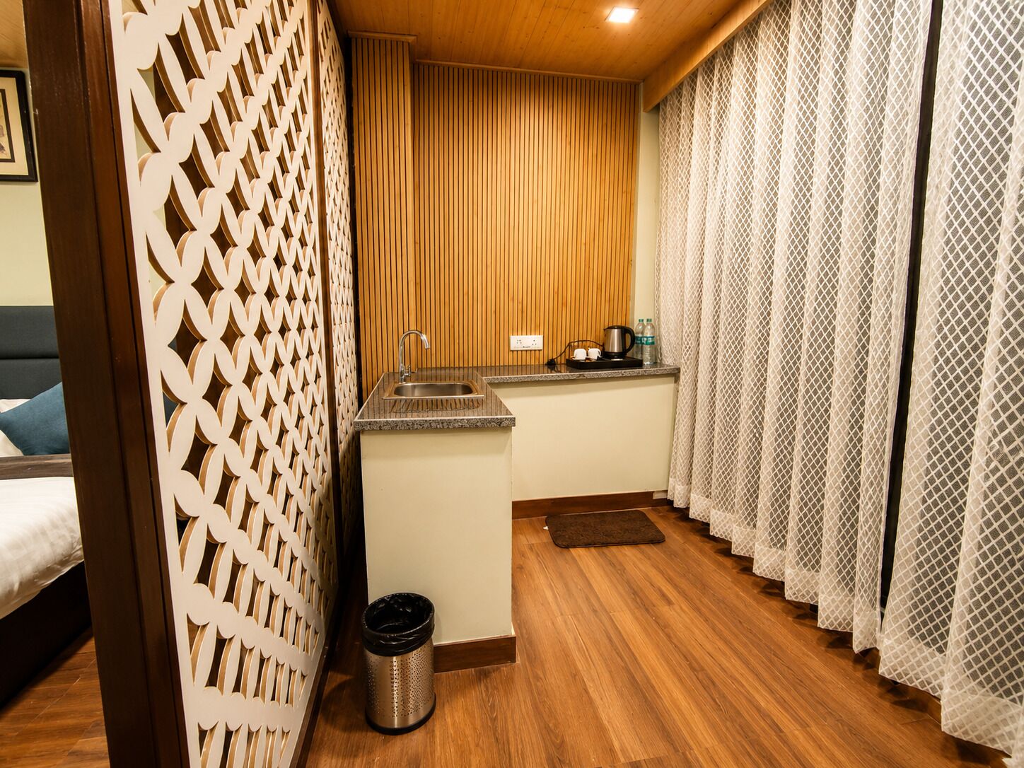 Cocina compacta con lavamanos, encimera y un pequeño cubo de basura.