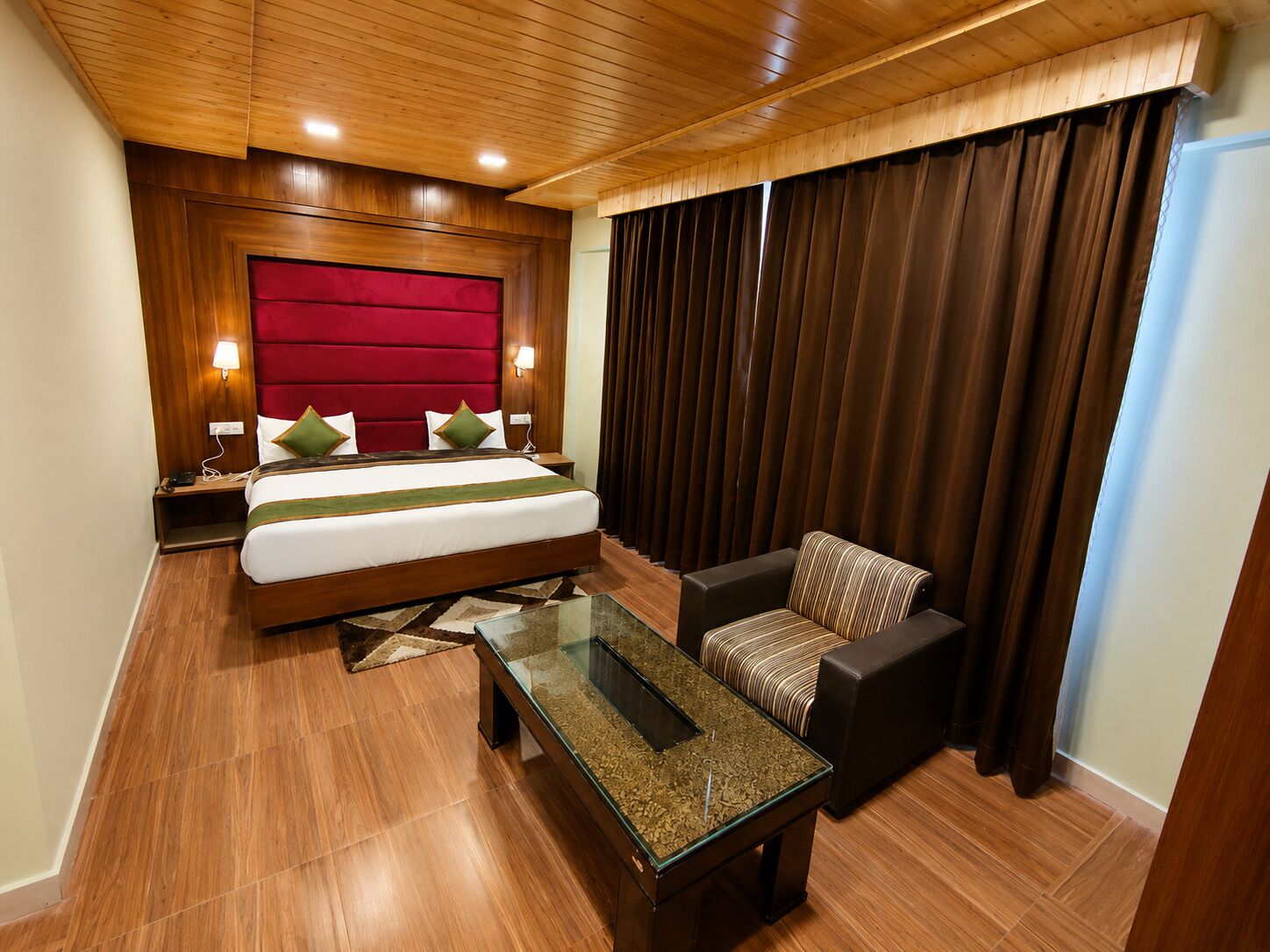 Habitación de hotel con una cama grande, una mesa de centro de vidrio, un sofá y vistas al exterior.