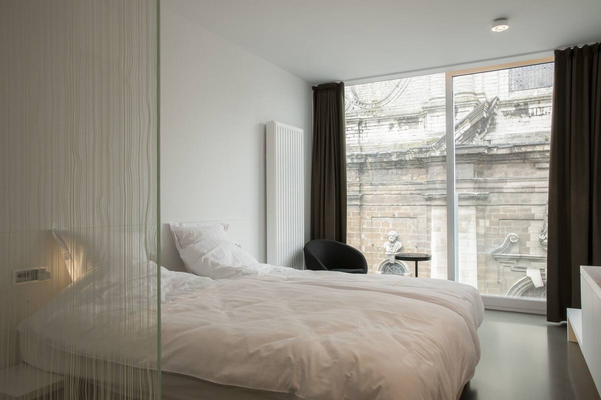A modern hotel room with a large bed, a small table, and a chair.