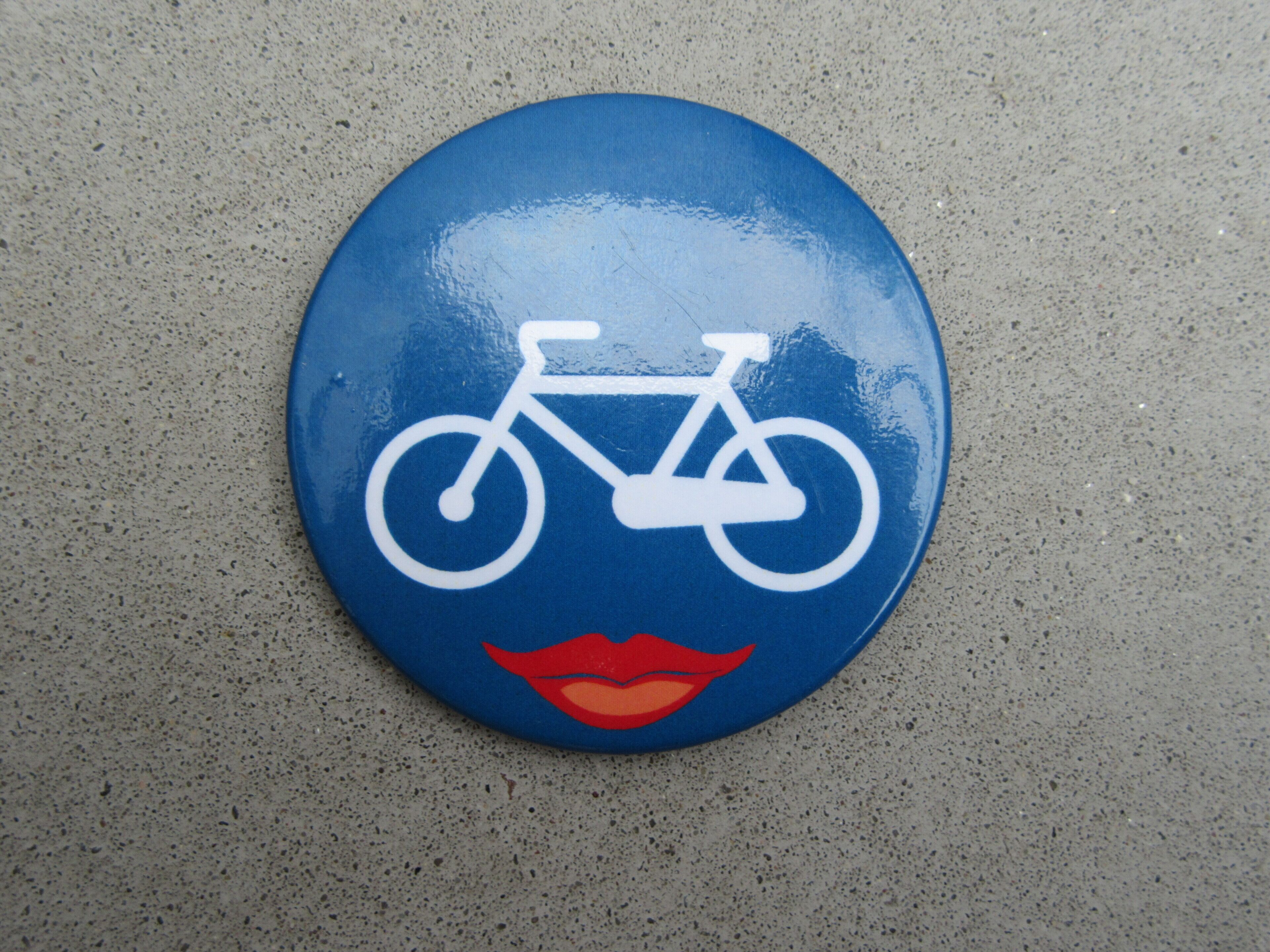 A blue sign with a white bicycle symbol and red lips.