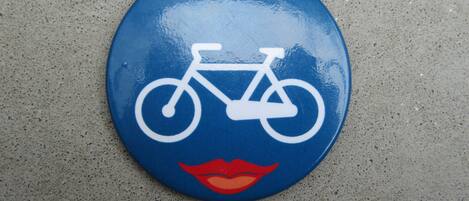 A blue sign with a white bicycle symbol and red lips.
