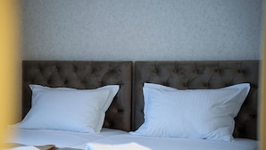 Ein Doppelbett mit gestepptem Kopfteil, weißer Bettwäsche und ordentlich gefalteten Handtüchern daneben.