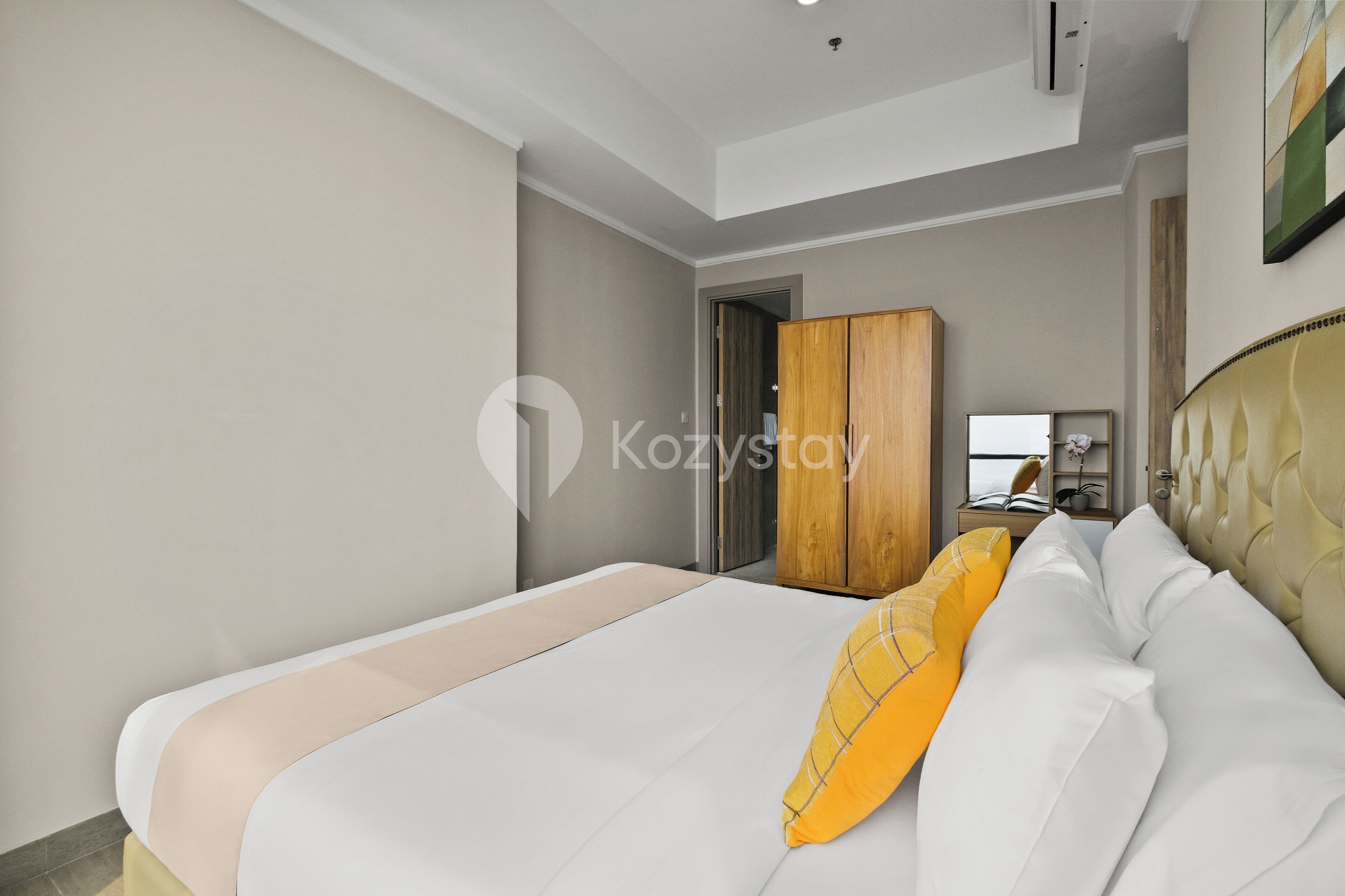 A modern hotel room with a large bed, a wooden wardrobe, and a small desk with a chair.