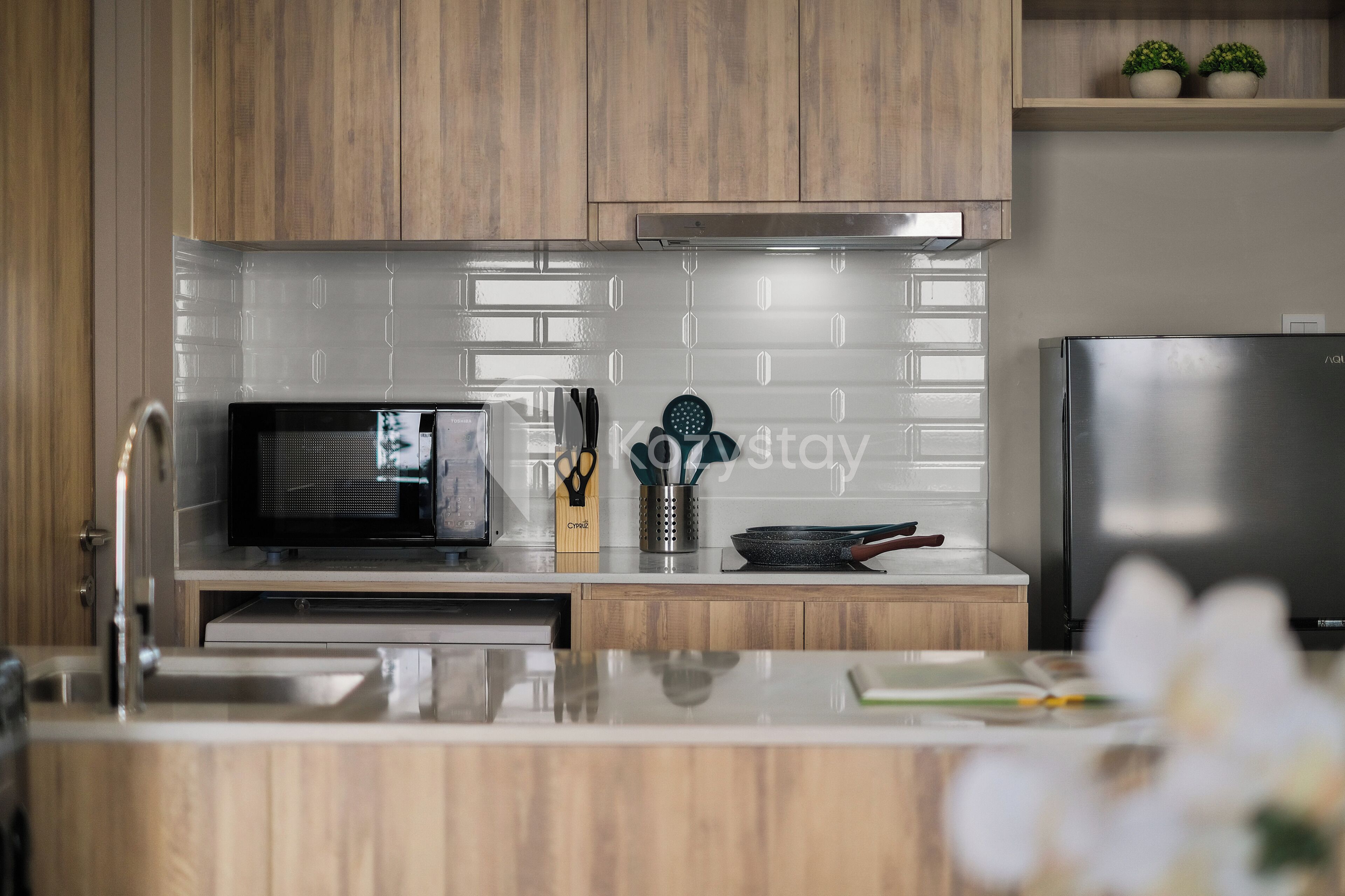 A modern kitchen with wooden cabinets, a stainless steel refrigerator, and a microwave.