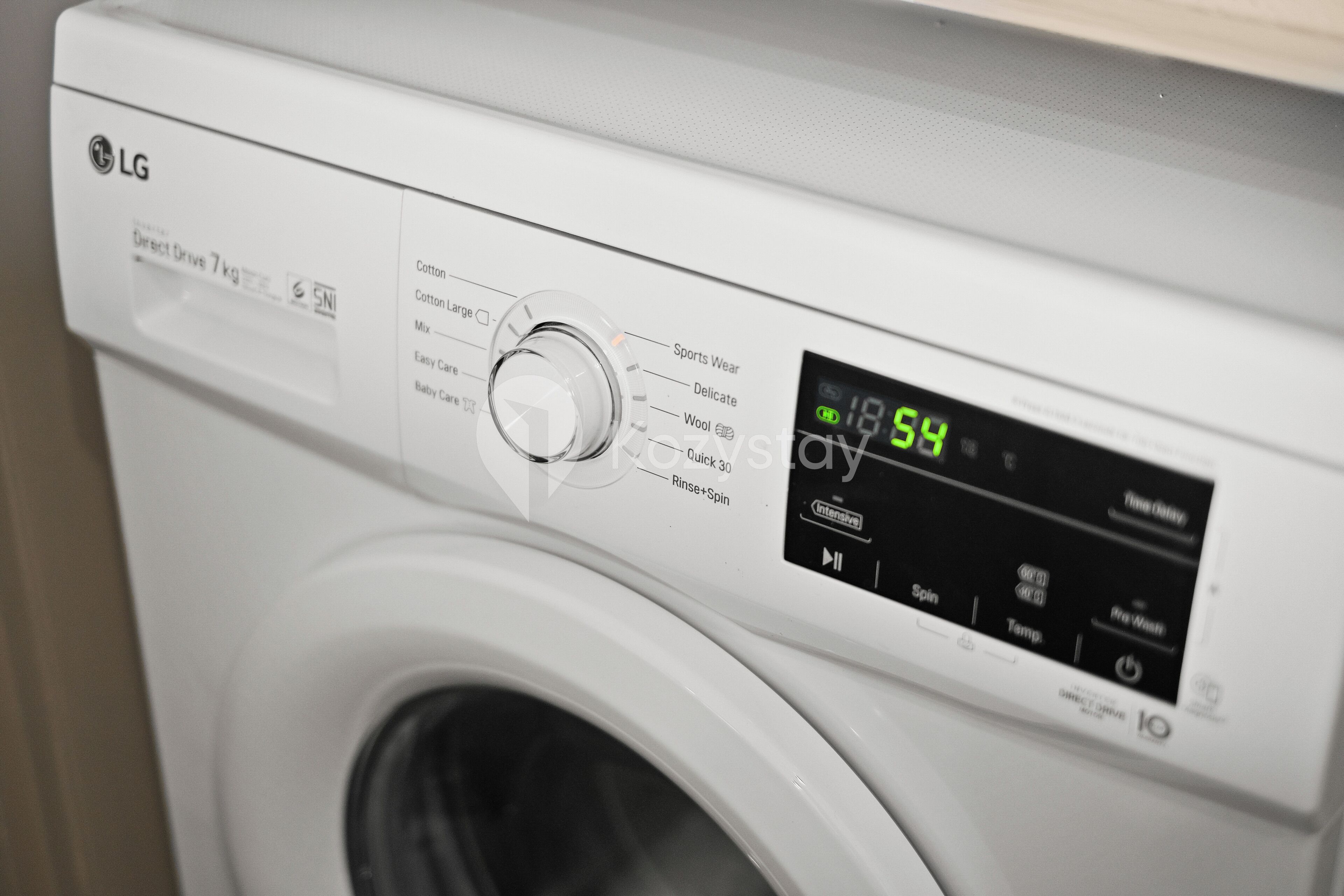 A white LG Direct Drive 7kg washing machine with a digital display showing 18:59.