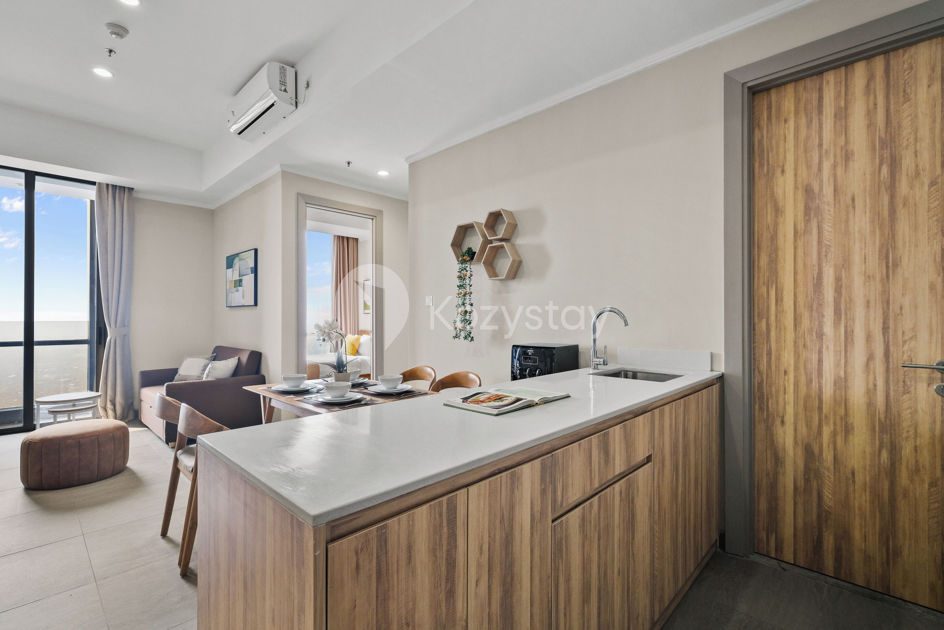 A modern kitchen with a central island, wooden cabinets, and a large window.