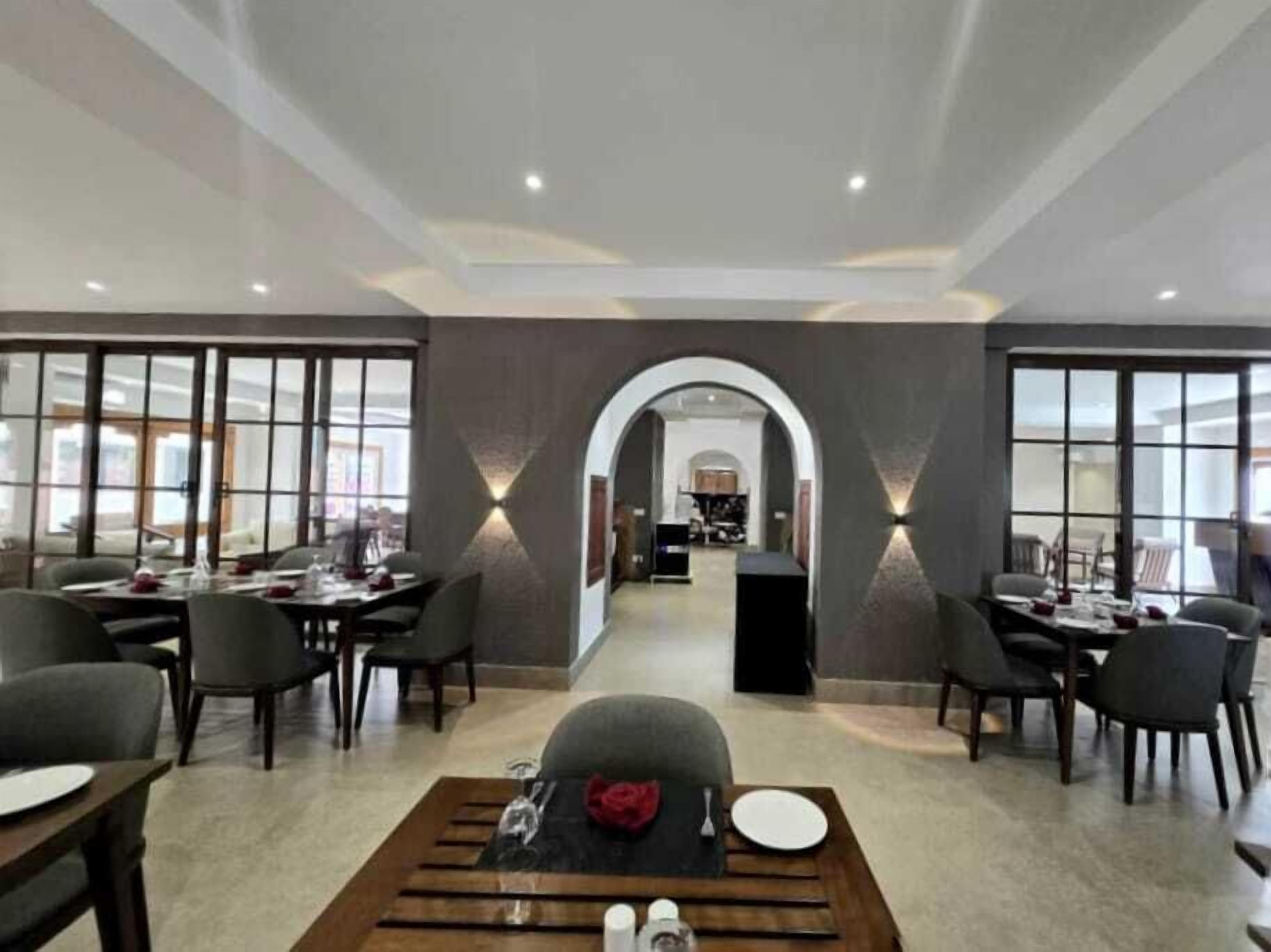 A spacious dining area with multiple tables and chairs, a central archway, and a view into another room.