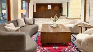 Een moderne lobby met een bank, fauteuils, een salontafel en een receptiebalie.