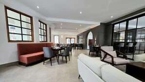 Een moderne hotellobby met een lange receptiebalie, zithoeken en grote ramen.