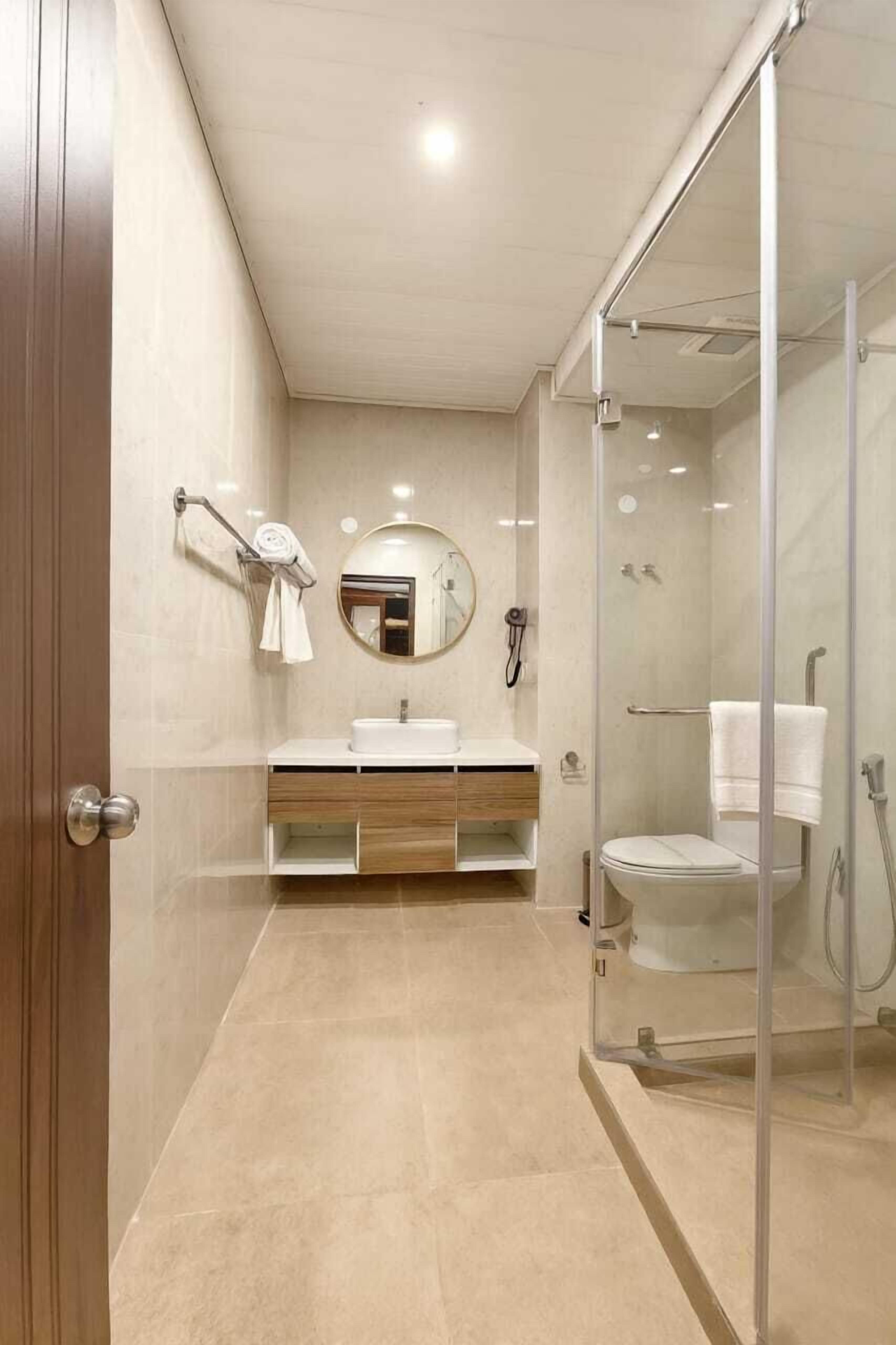A modern bathroom with a glass shower enclosure, a wooden vanity, and a large mirror.