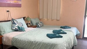 A room with two beds, a nightstand, a lamp, a painting, and an air conditioning unit. - 1 Showgrounds Road Horse Creek QLD 4714 (Horse Creek)