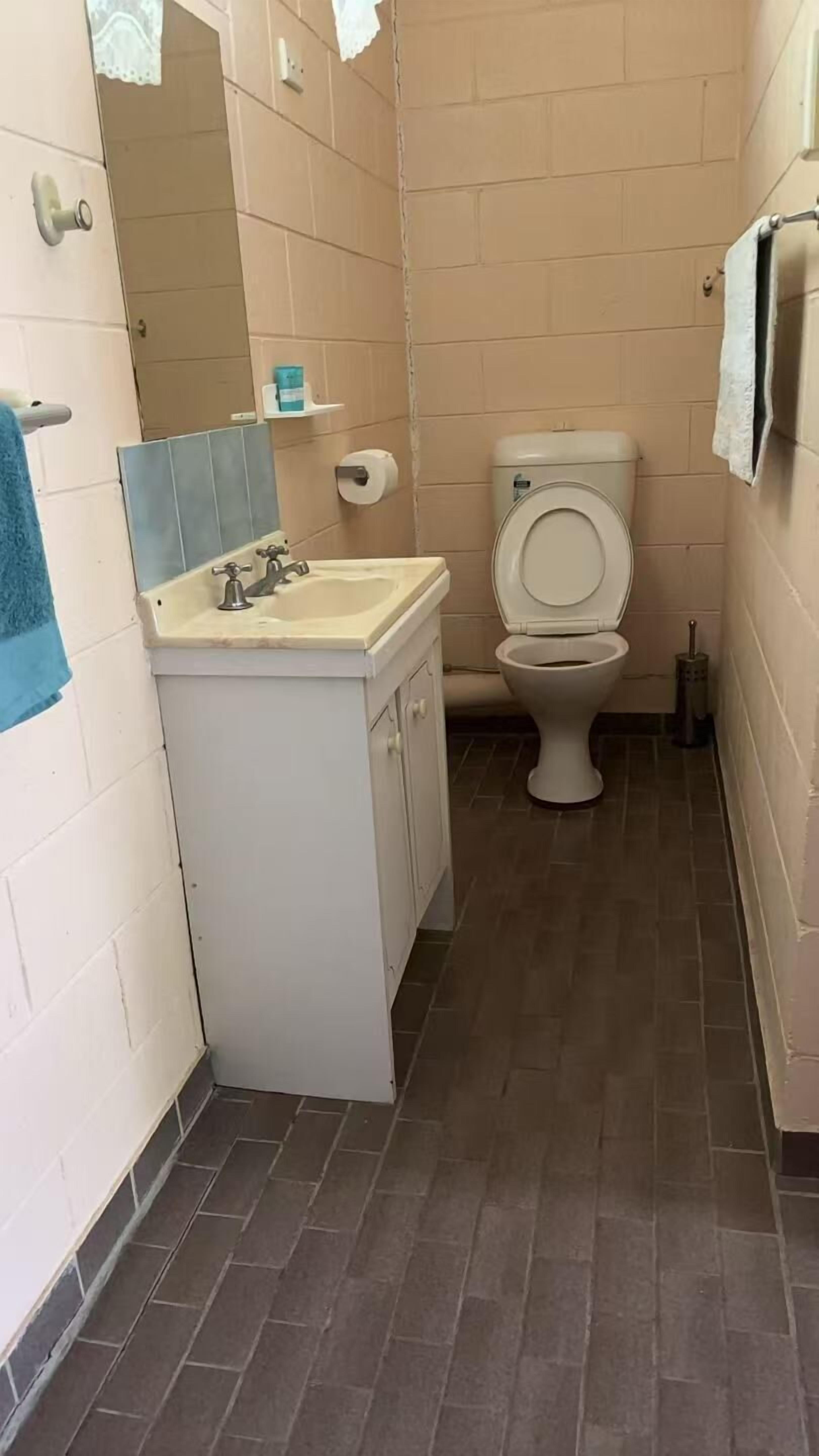 Un bagno piccolo con il water, lavandino e specchio.