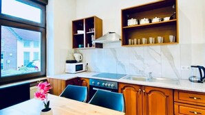 Een moderne keuken met houten kastjes, een marmeren achterwand en een eethoek met een tafel en stoelen.