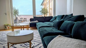 A modern living room with a dark green sofa, a round coffee table, and a patterned rug.