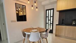 A dining area with a round wooden table, white chairs, and a modern kitchen with wooden cabinets and a black countertop.