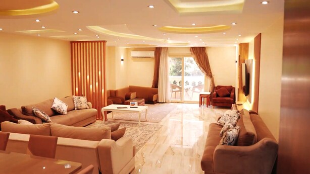 A modern living room with a sofa set, a coffee table, and a television. - Premium Swiss Residence Mohandessin (Cairo)