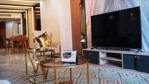 A modern living room with a large flat-screen TV, a glass coffee table, and a calendar on the wall. - Premium Swiss Residence Mohandessin (Cairo)
