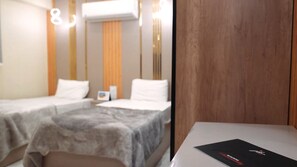 A hotel room with two beds, a wooden panel wall, and a table with a black booklet. - Premium Swiss Residence Mohandessin (Cairo)