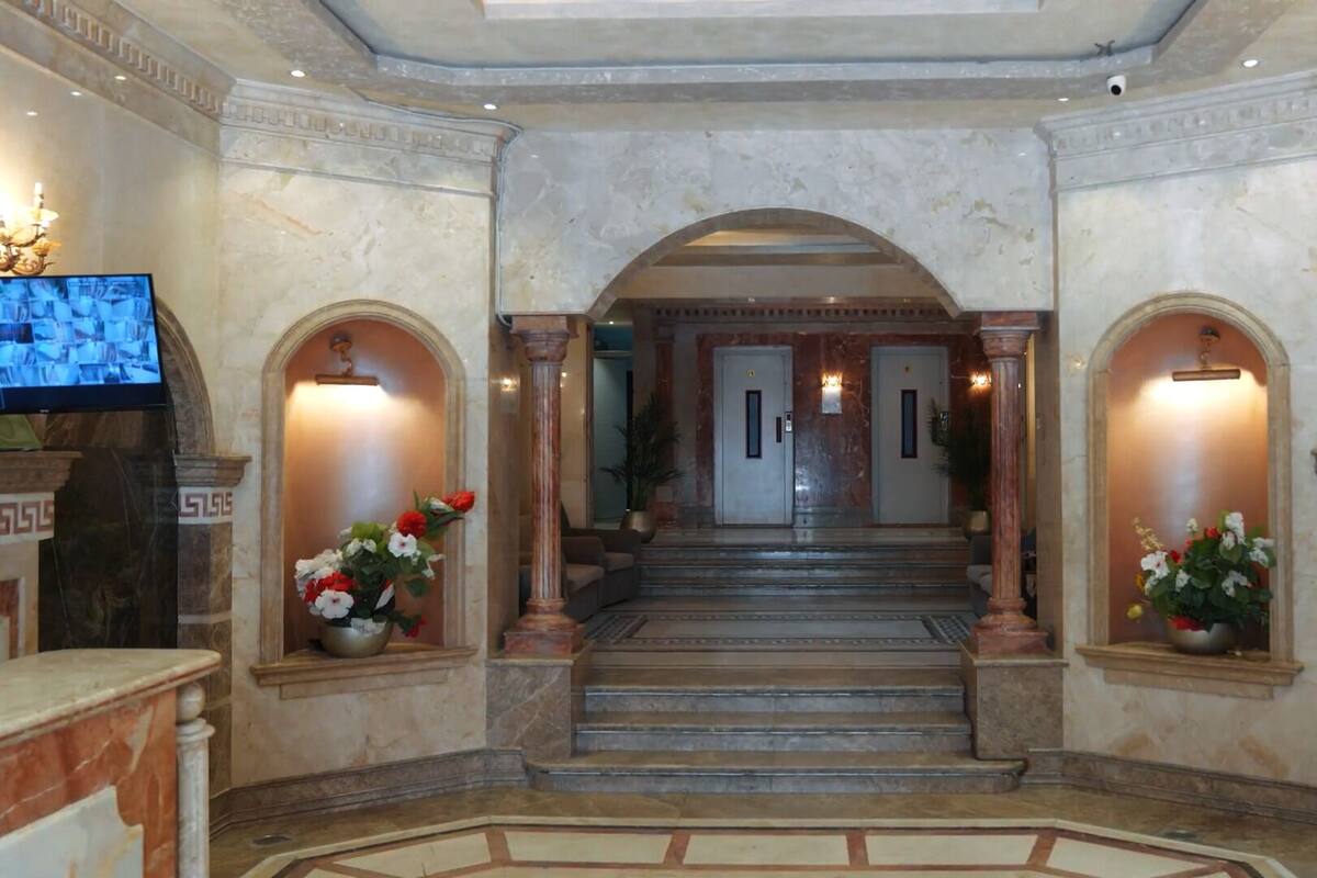 A grand hallway with marble floors, a central staircase, and two columns on either side.